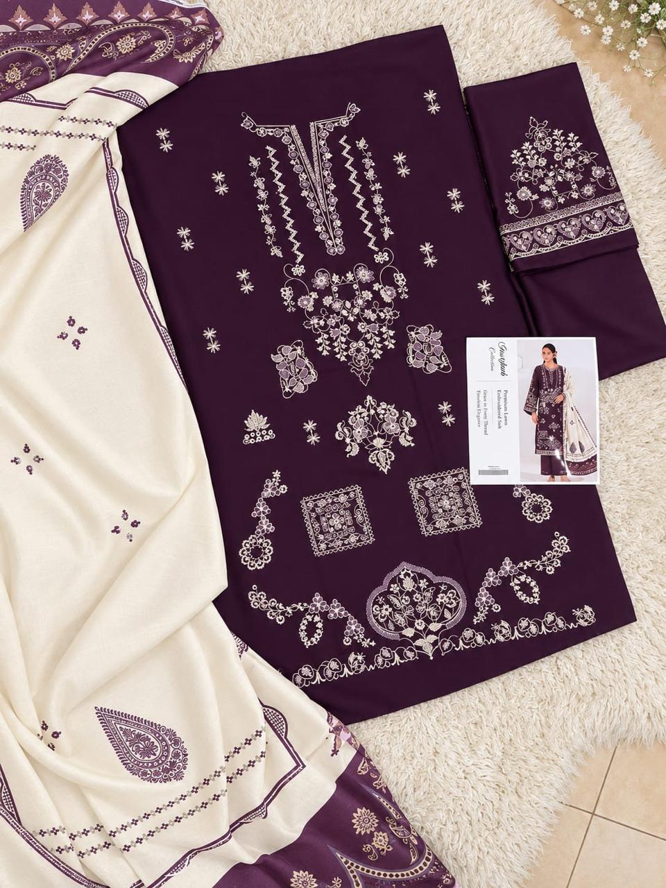 A flat-lay presentation of a three-piece Pakistani ethnic suit set, featuring a deep purple kurta with intricate silver embroidery, matching purple trousers, and a cream-colored dupatta with purple borders and motifs, displayed on a white faux fur rug.
