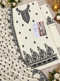 An off-white Pakistani ethnic shalwar kameez suit set with black printed embroidery, featuring a kurta, matching trousers, and a dupatta, styled with decorative flowers and a lantern.