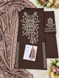 A flat-lay presentation of a brown three-piece salwar kameez suit set, featuring a kurta with intricate white floral embroidery, matching trousers, and a dupatta with matching floral patterns. A small brand card is visible on the kurta.